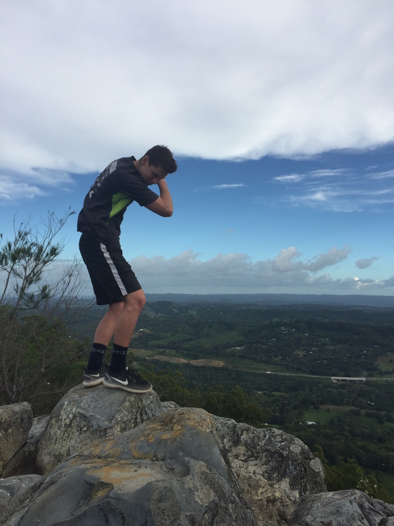 Young person on a rocky outcrop above a wide green valley